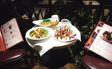 Выносной стол, сервированный муляжами блюд и напитков перед входом в кафе