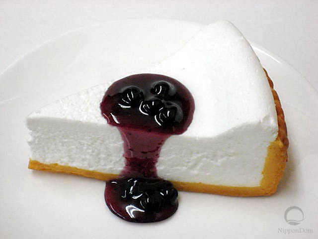 A replica of white cheesecake with bilberry sauce 