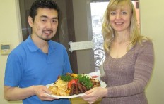 The factory worker is passing a fake food dish for sending to the customer.